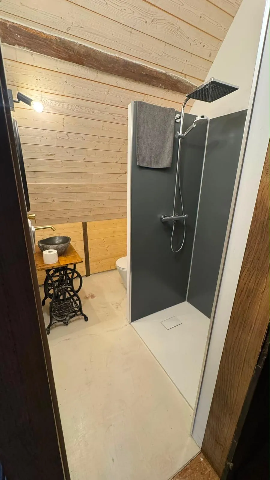 Salle d’eau sous les combles, lambris clair, douche à l’italienne et vasque en pierre