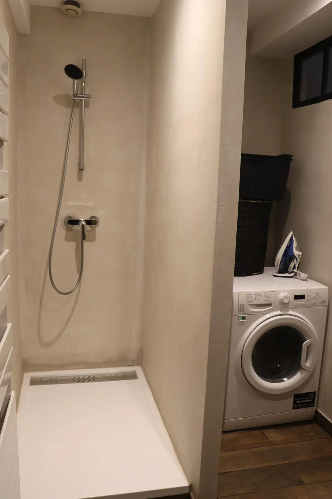 Douche à l’italienne en béton ciré, avec le lave-linge dans le renfoncement voisin