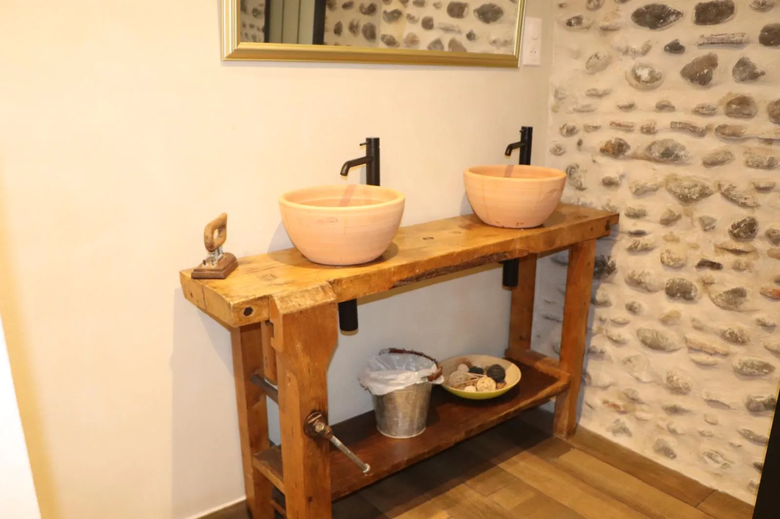 Établi ancien transformé en meuble de salle de bain, deux vasques et mitigeurs noirs, mur de galets