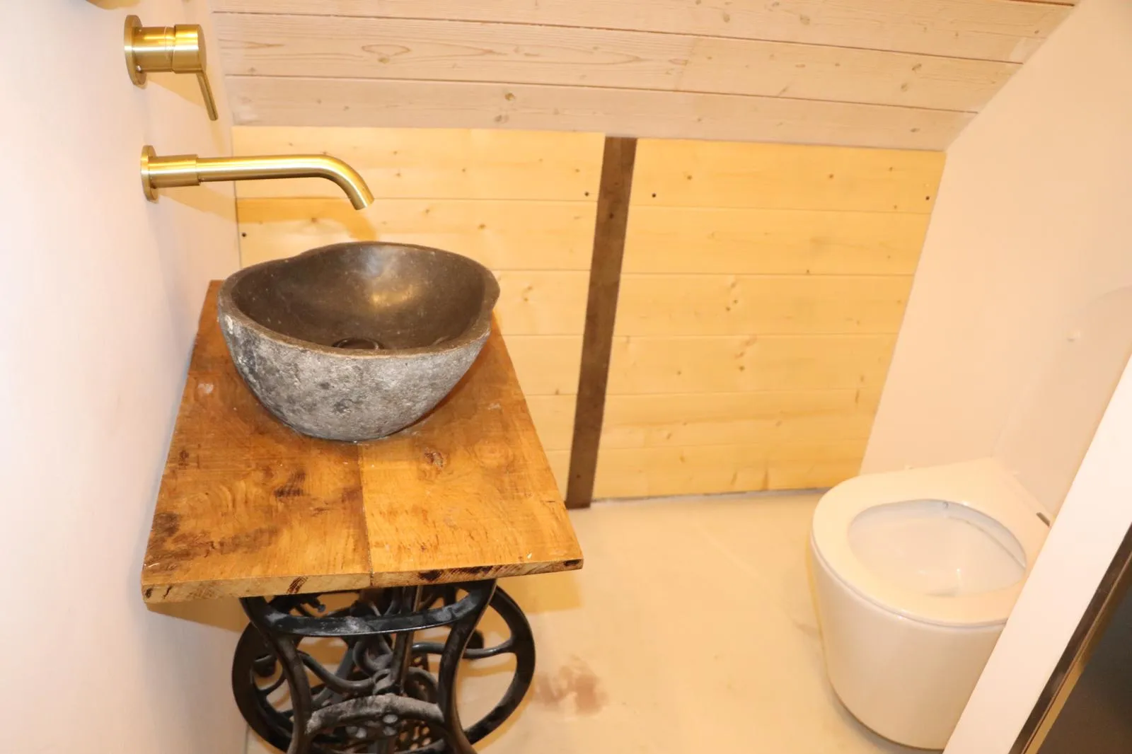 WC avec vasque en pierre posée sur un piètement de machine à coudre en fonte