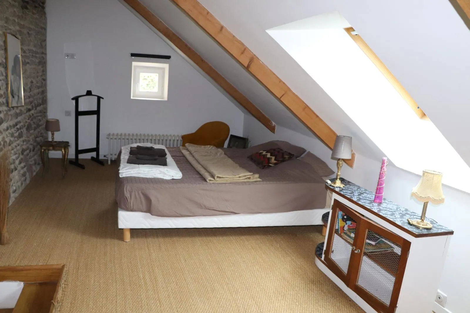 Chambre sous rampants avec poutre apparente et fenêtre de toit