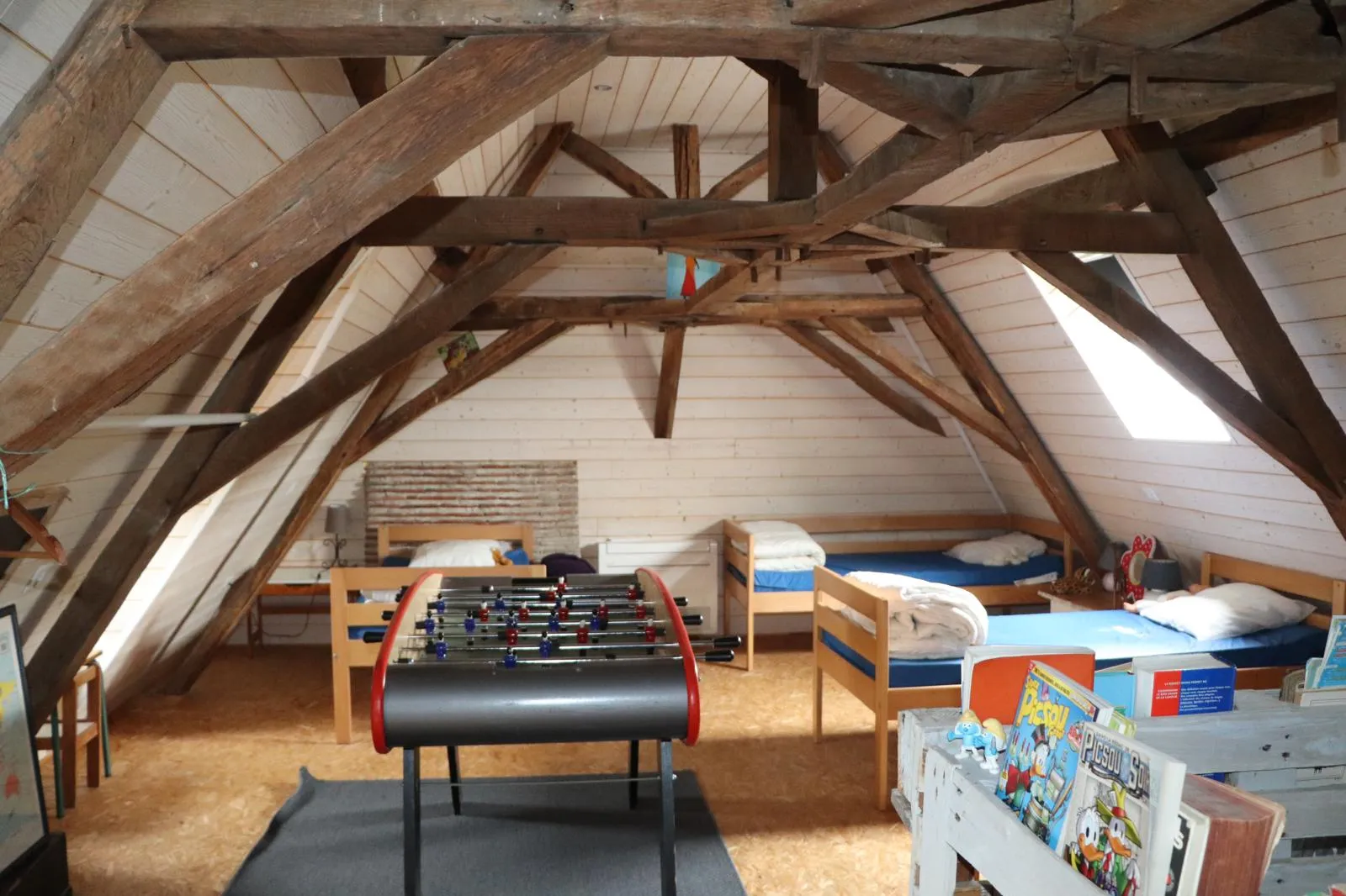 Baby-foot installé au milieu du dortoir, lits simples de part et d’autre