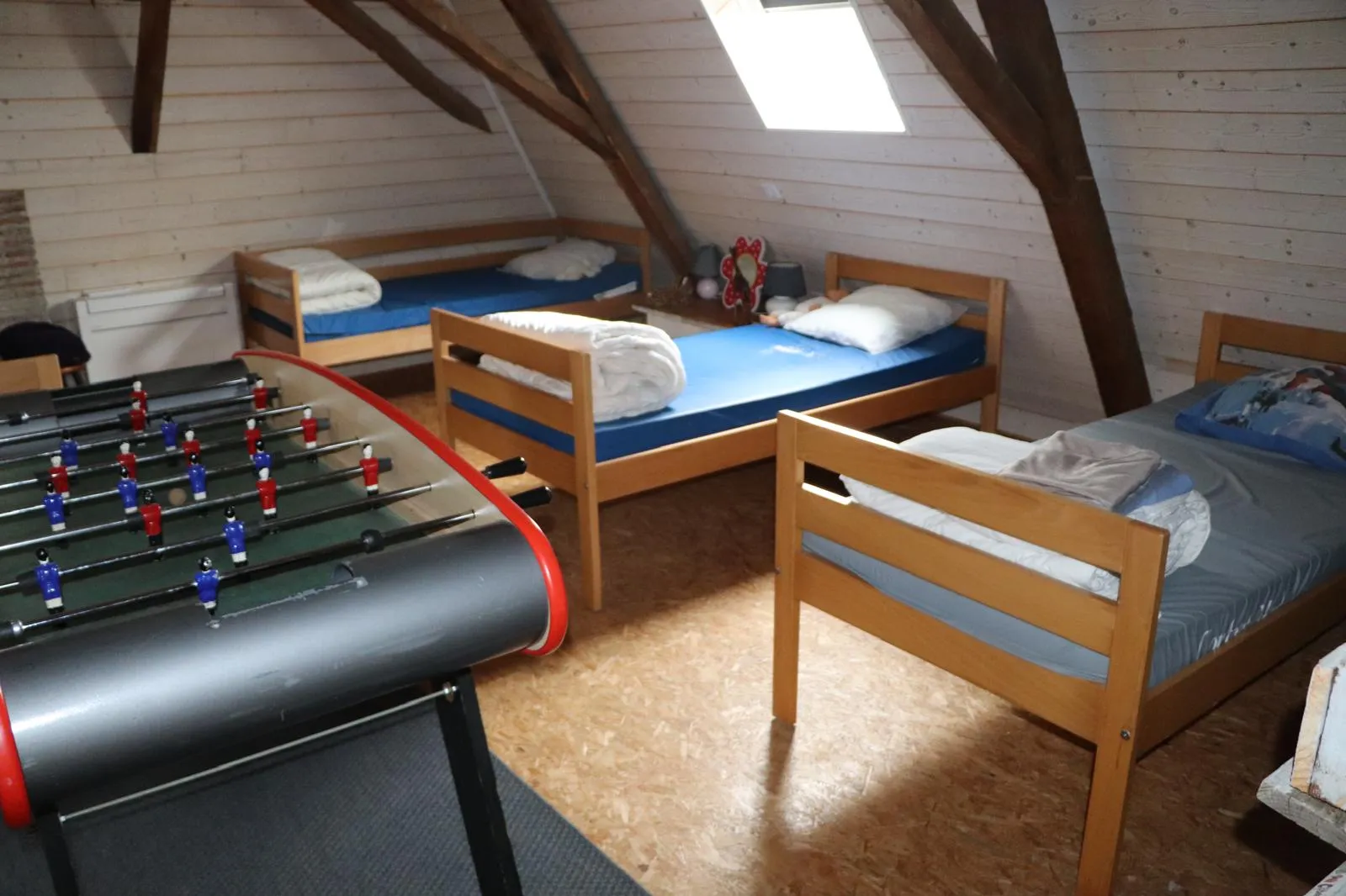 Lits simples du dortoir sous les rampants, avec le baby-foot au premier plan