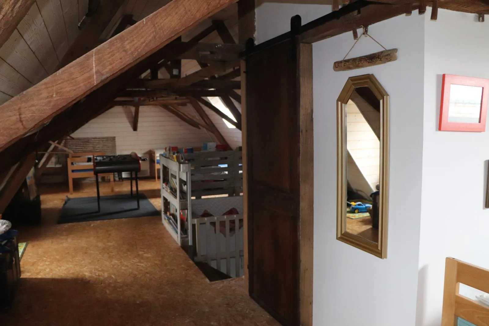 Porte ancienne montée en coulissant sur rail, séparant deux espaces sous les combles