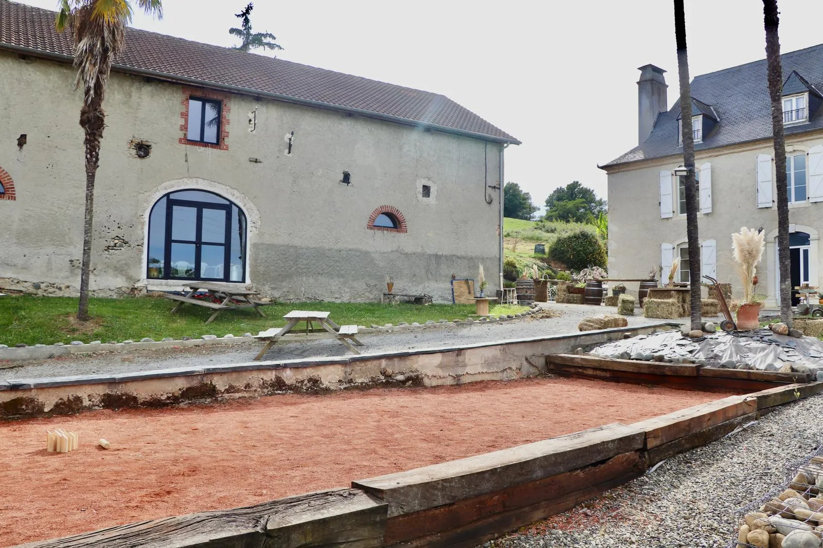 La grange rénovée et sa grande baie vitrée, avec le terrain de pétanque au premier plan