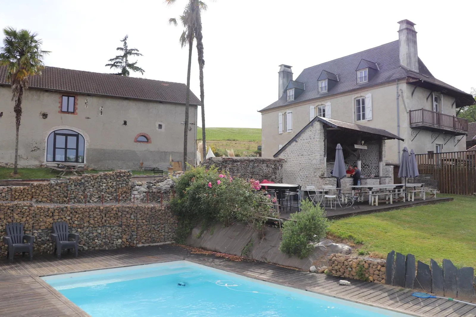 La piscine au premier plan, la grange à gauche et la maison de maître à droite