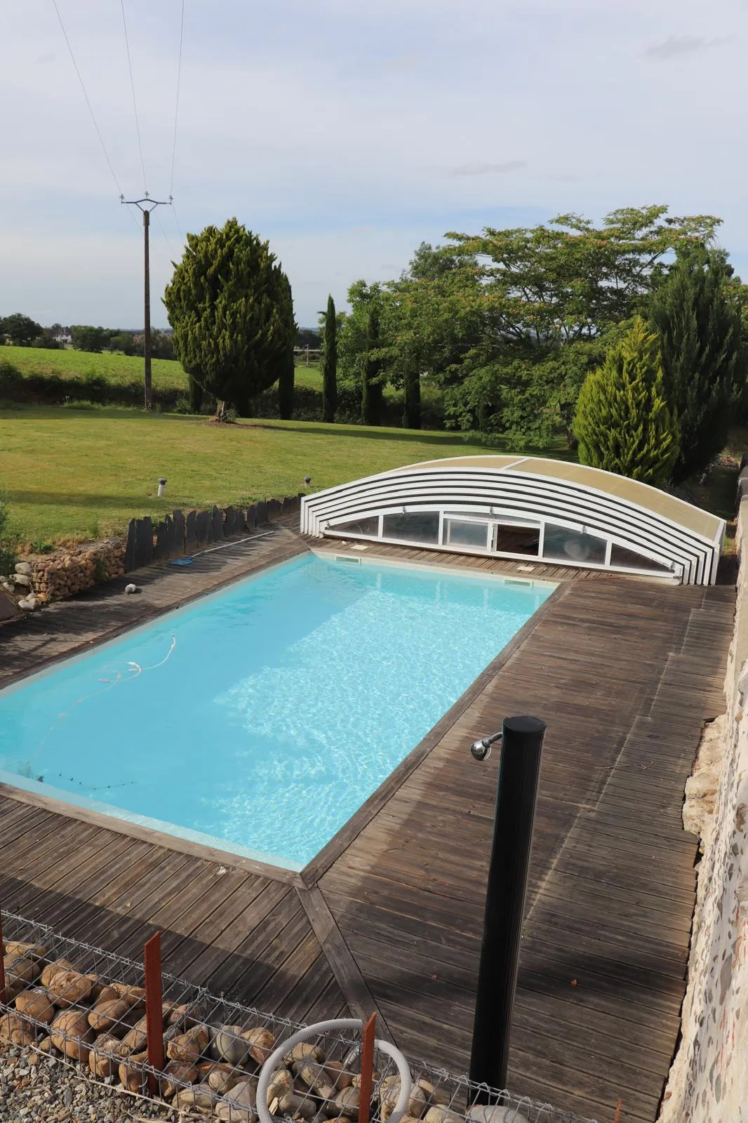 La piscine vue depuis la terrasse haute, ouverte sur les prés et les bosquets