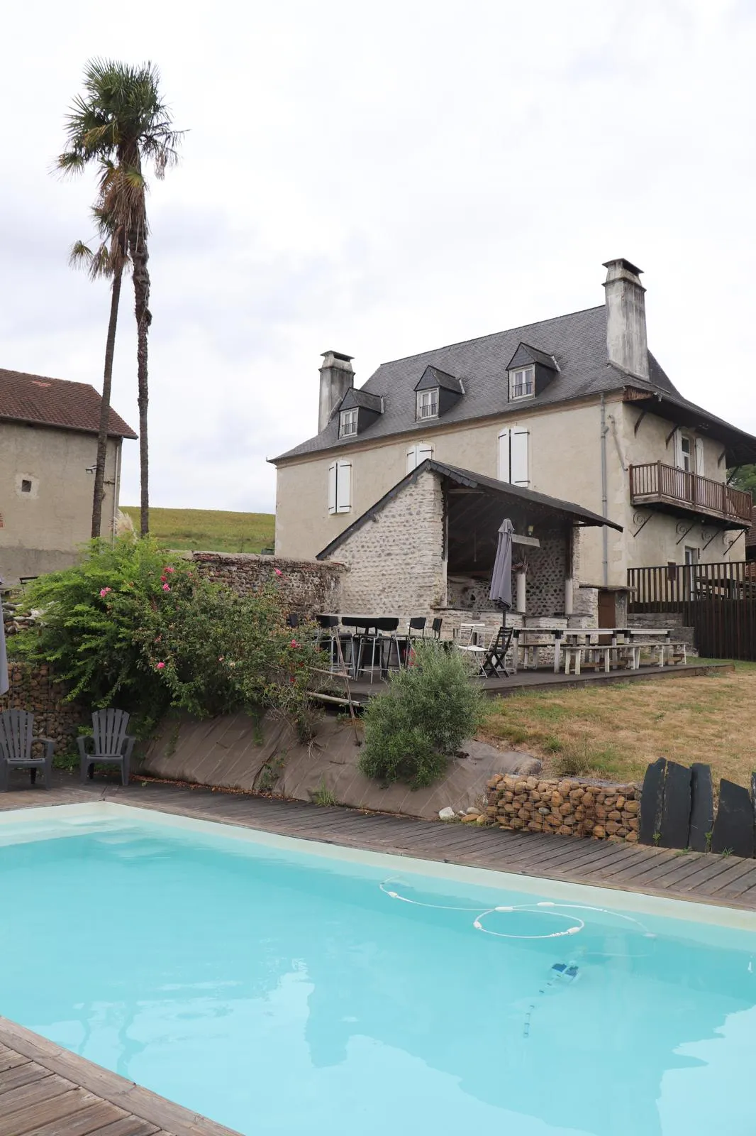 La maison béarnaise et sa terrasse vues depuis le bord de la piscine
