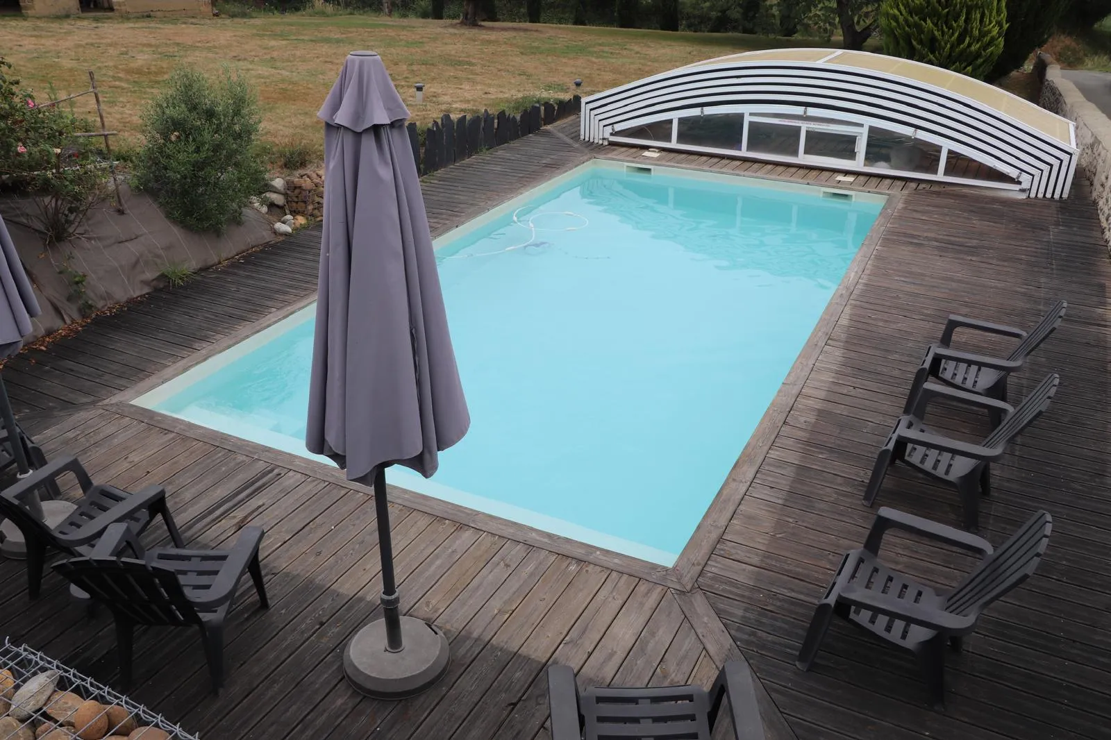 Transats et parasol autour de la piscine, sur la terrasse en bois