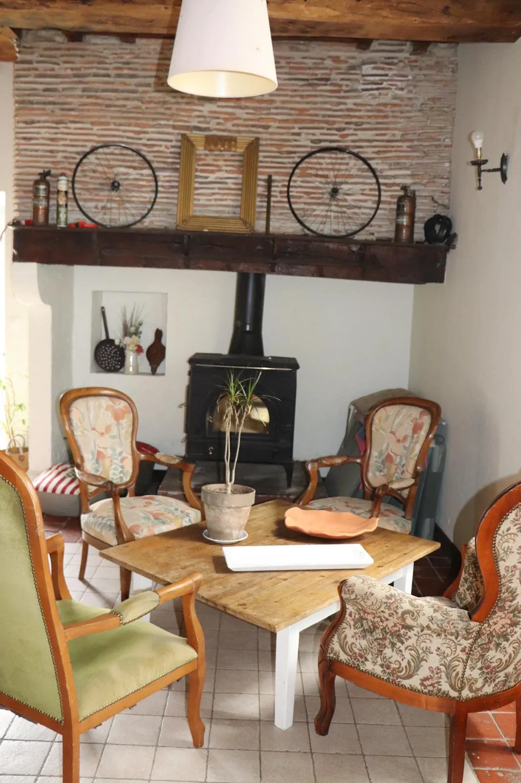 Fauteuils anciens disposés autour d’une table basse en bois, devant le poêle à bois