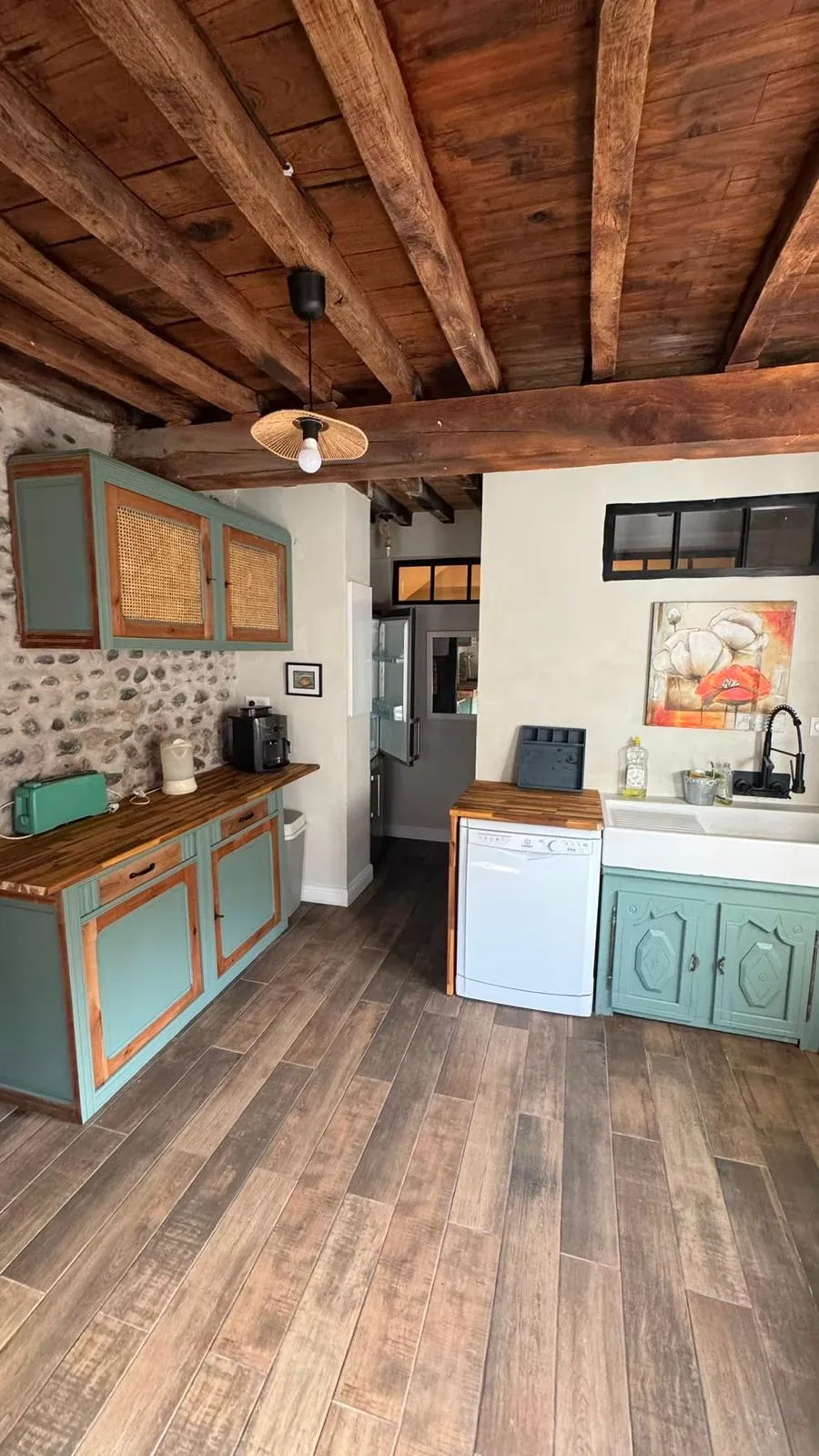 Cuisine sous plafond à poutres apparentes, meubles bleu-vert et plans de travail en bois
